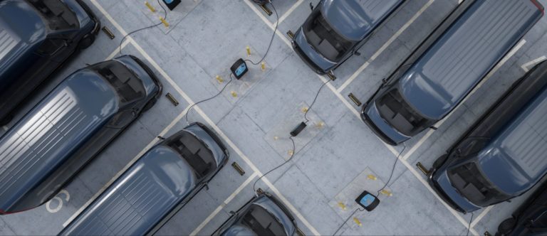 Zwarte elektrische bestelwagens staan op een parking naast en tegenover elkaar terwijl ze opladen.