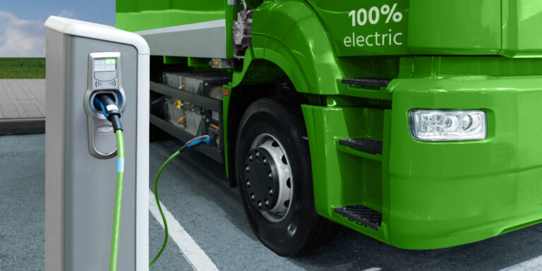 Un camion électrique vert qui se recharge à une borne de recharge.