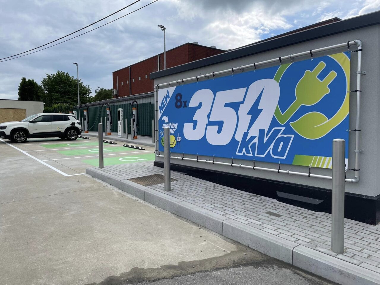 Nouvelle infrastructure de recharge sur la place de recharge de la station Interzonings. Une voiture blanche charge à l'aide d'une borne de recharge de Kempower.