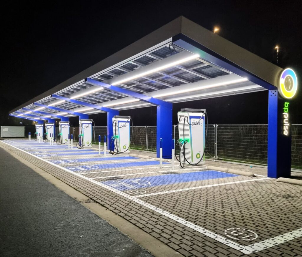 Een verlicht laadplein in het donker met een solarluifel en 6 snelladers van Alpitronic.